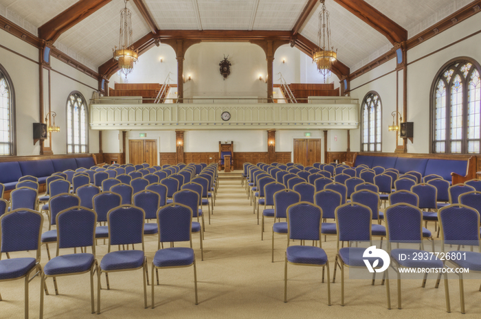 Auditorium with blue chairs, and a stage with curtains