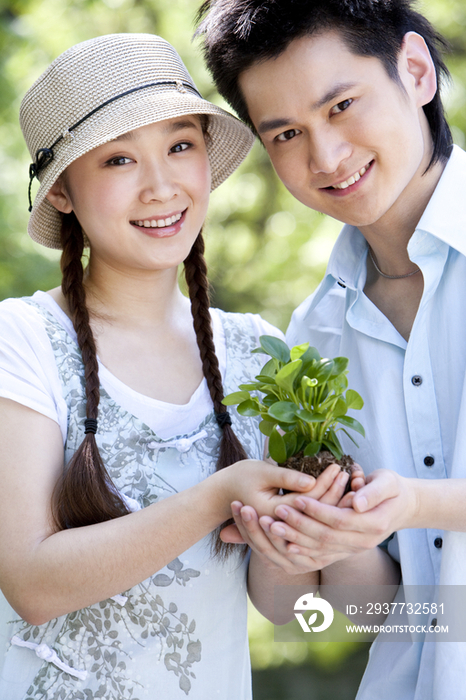 年轻情侣手捧植物