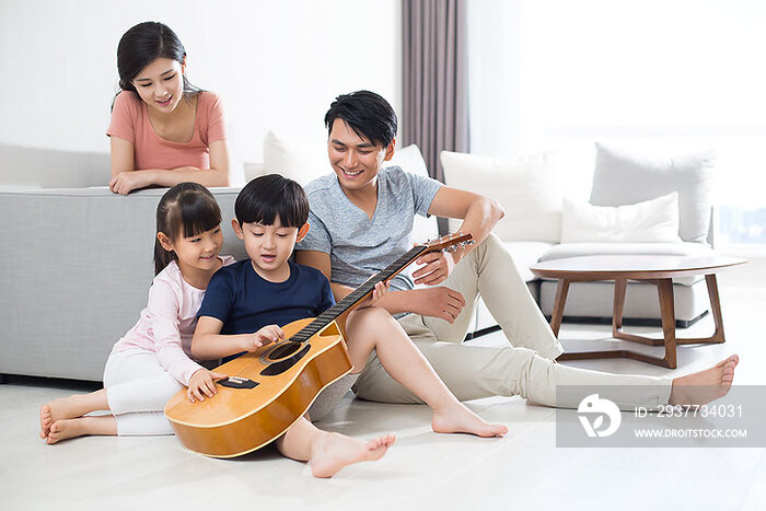 快乐的年轻家庭在家弹奏吉他