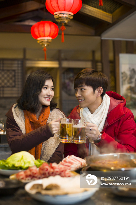 年轻情侣在火锅店吃饭喝啤酒