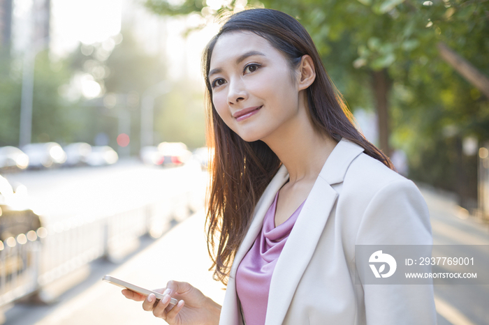 年轻女子拿着手机等出租车