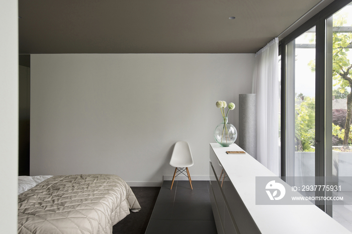 View of a cropped bed along large window in bedroom at contemporary house