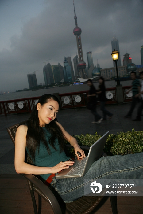 外滩黄浦江边一位女青年在桌旁使用笔记本电脑