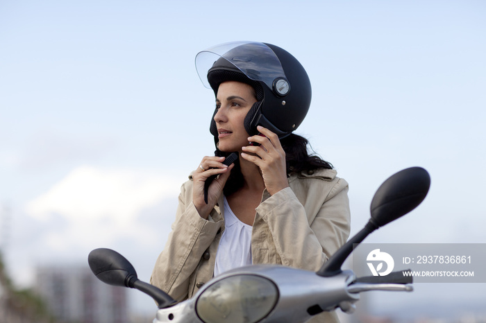 迷人的夫人auf Roller zieht ihren Helm aus