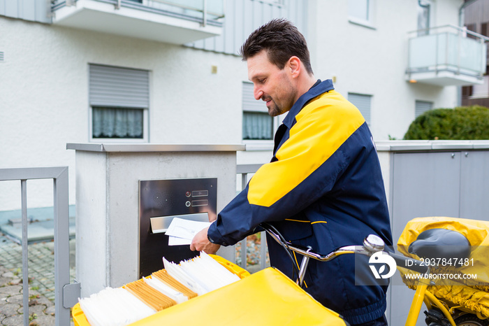 Postbote bei Zustellung von Briefen an Briefkasten von Empfänger