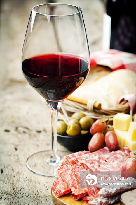 Glass of red wine with charcuterie assortment on the background