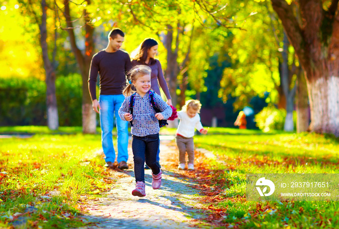 快乐的小女孩在秋天公园跑步与她的家人为背景