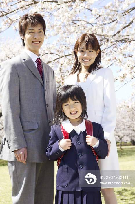 站在樱花前的小学生女子及其父母