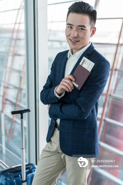 年轻商务男士在机场拿着护照和机票 