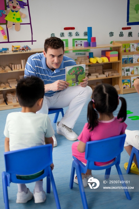 幼儿园外教男老师和小朋友们一起看画册